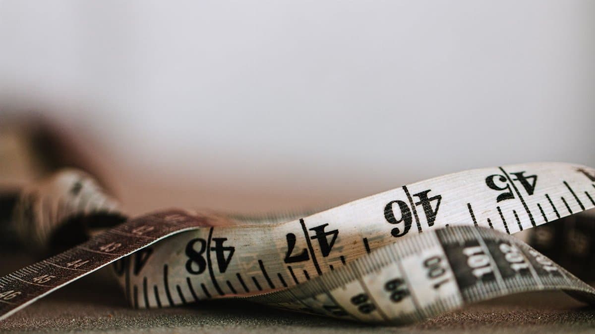 Extreme close-up shot of a coiled measuring tape showing numbers in inches and centimeters.