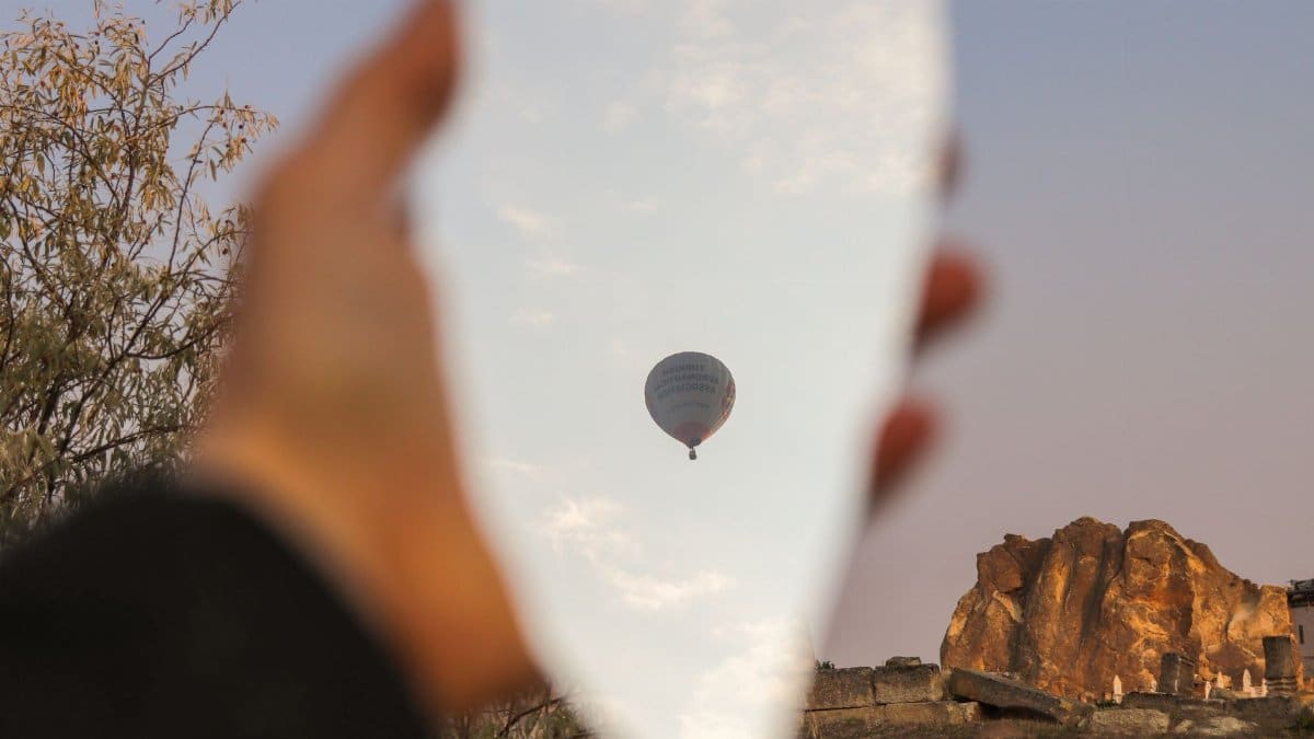 Creative view of hot air balloon reflected in a piece of broken mirror outdoors.