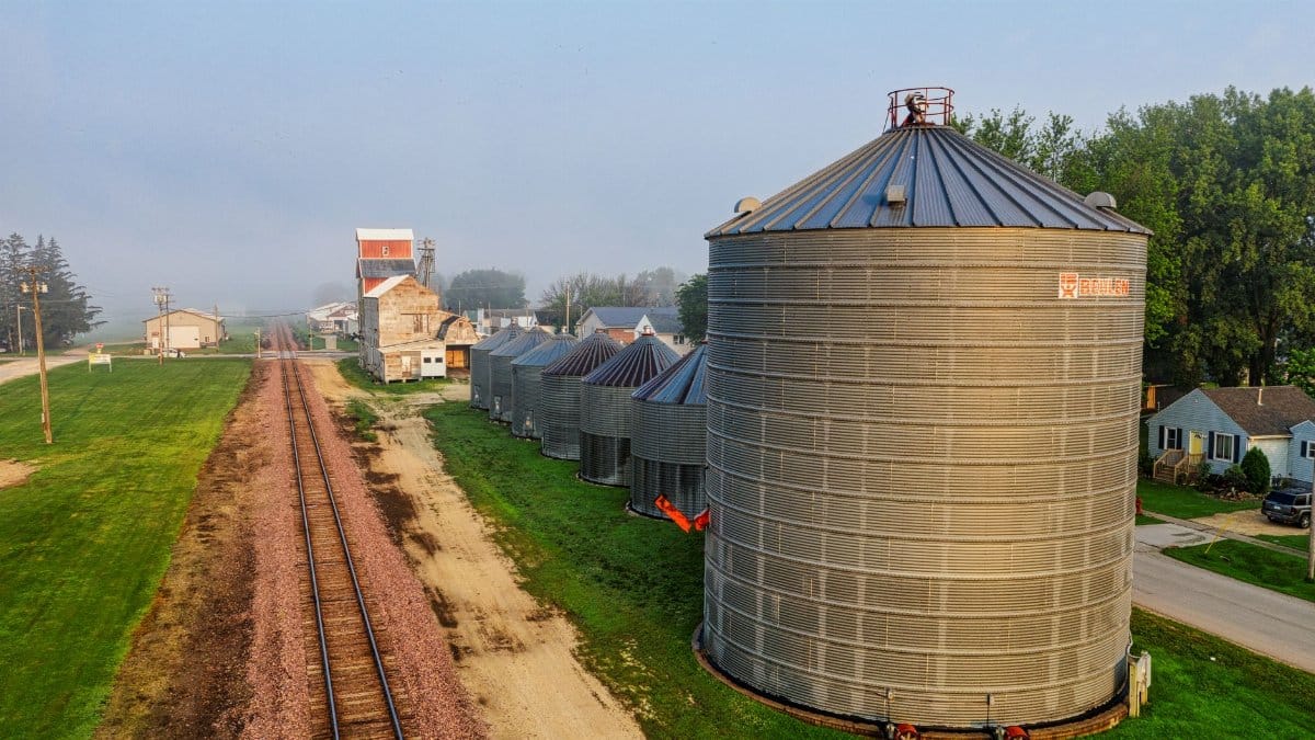 Aerial shot capturing grain silos and railroad tracks in rural Utica, Minnesota.