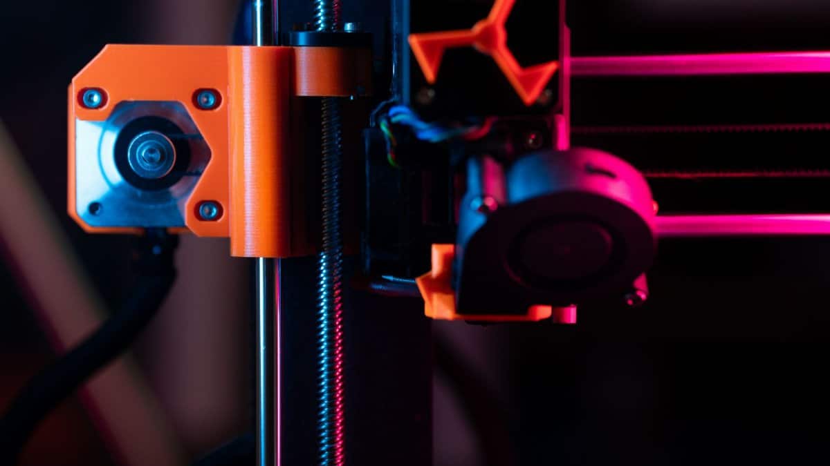 A detailed close-up of a 3D printer showcasing its extruder and components under vibrant lighting.