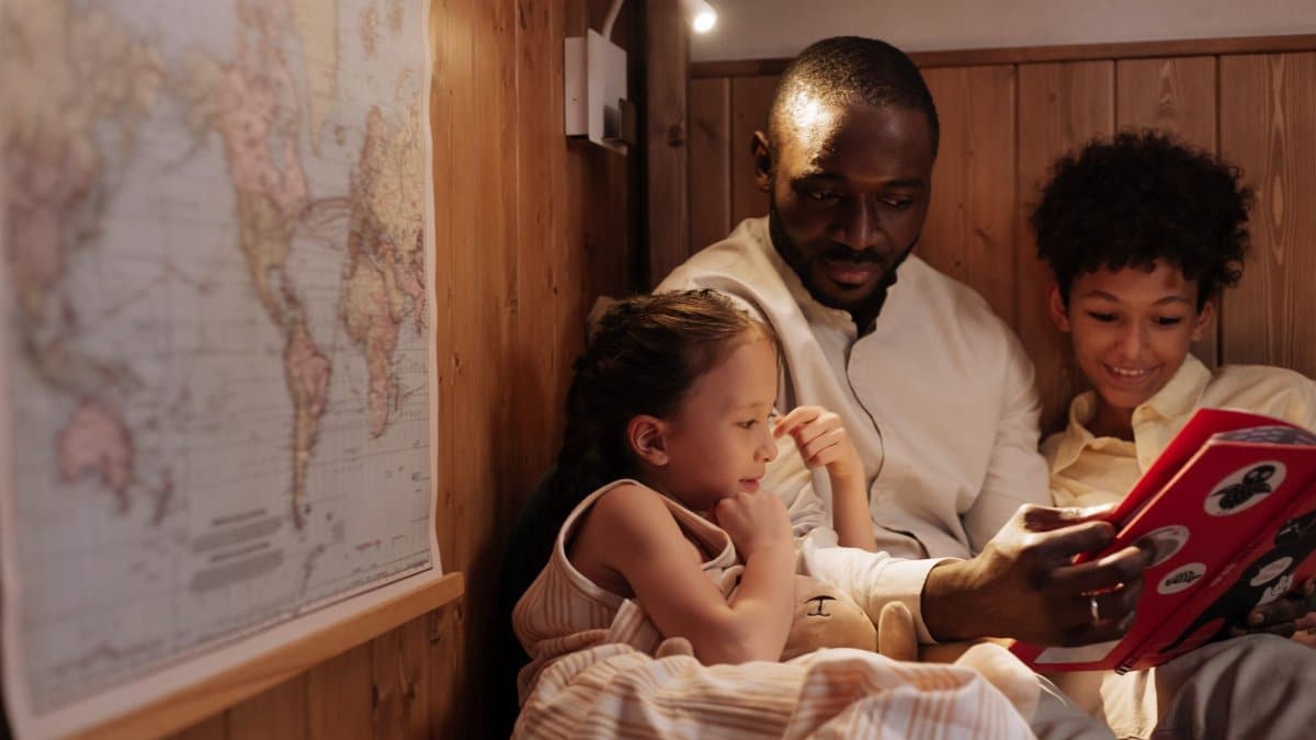 A father reads a bedtime story to his two children, creating a moment of bonding and warmth indoors.
