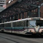 Light rail train at city station with modern urban background during the day.