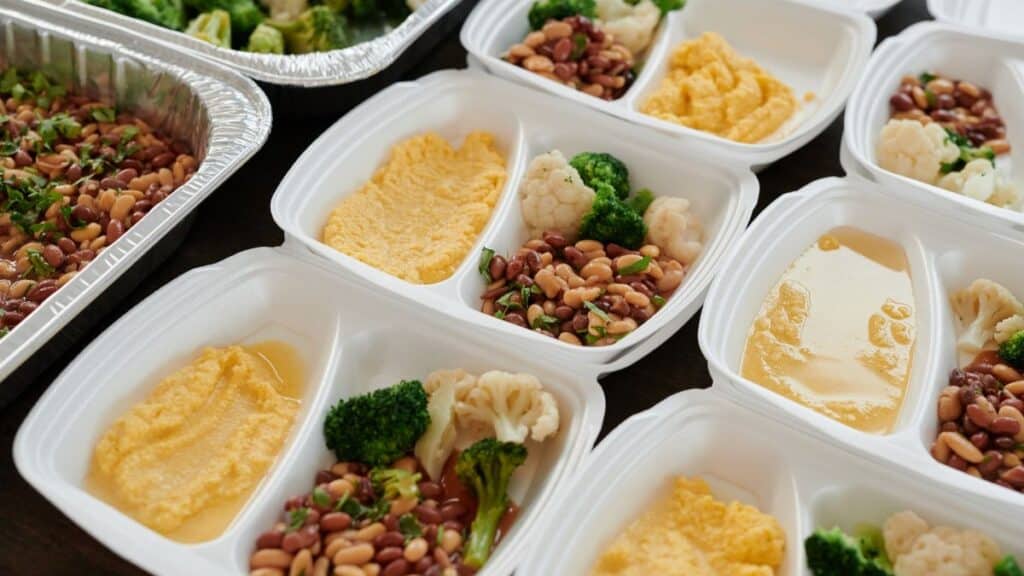 Assorted meal prep containers with beans, broccoli, and mashed potatoes, perfect for healthy eating.