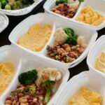 Assorted meal prep containers with beans, broccoli, and mashed potatoes, perfect for healthy eating.