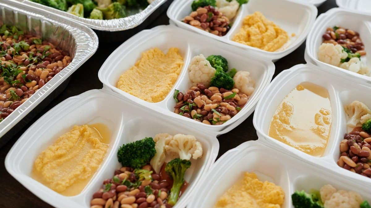 Assorted meal prep containers with beans, broccoli, and mashed potatoes, perfect for healthy eating.