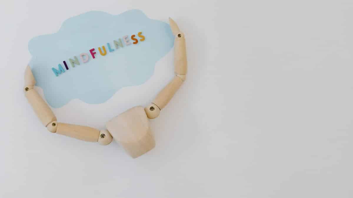Wooden mannequin holding a mindfulness speech bubble for relaxation and mental health concepts.