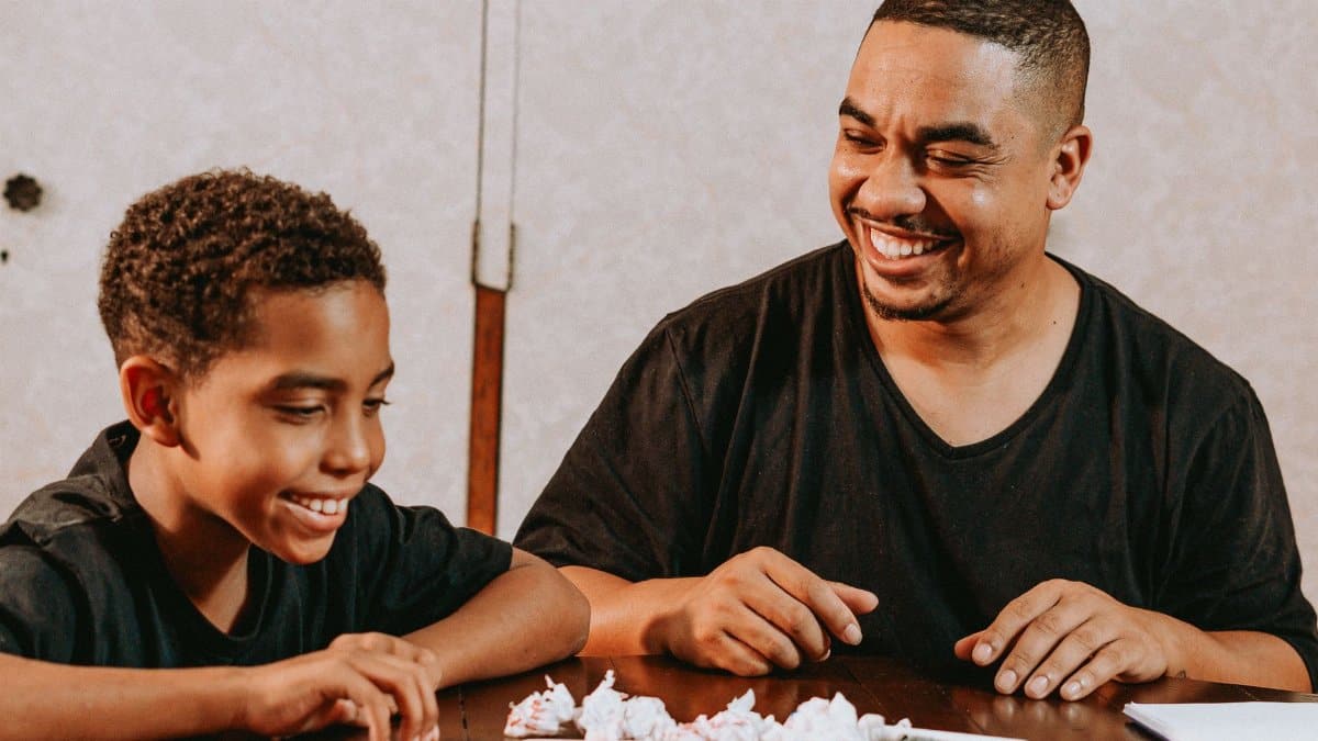 Father and son joyfully engaging in creative activities indoors, fostering connection and learning.