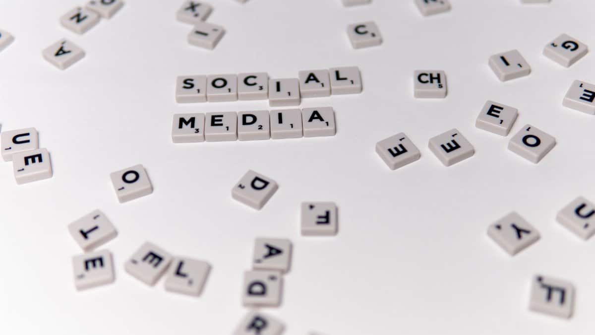 White Scrabble tiles forming the phrase 'social media' on a scattered background.