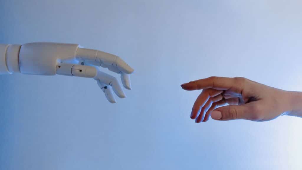 A human hand reaching towards a robotic hand symbolizing technology and connection.