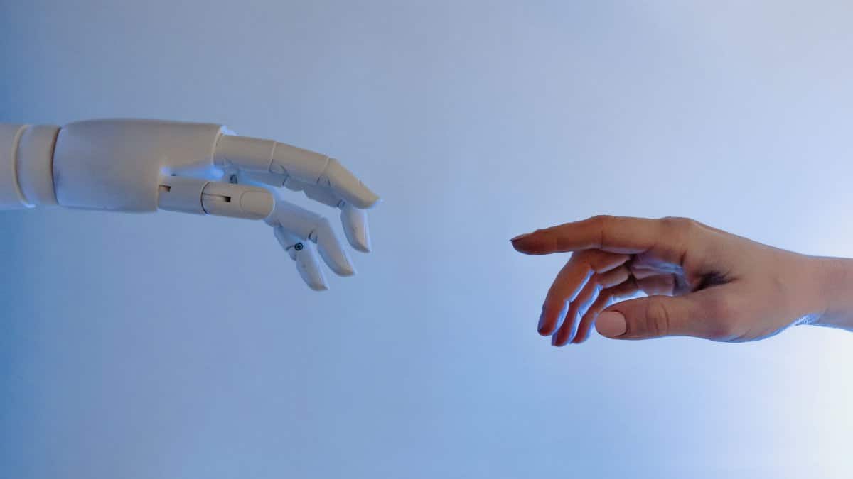 A human hand reaching towards a robotic hand symbolizing technology and connection.