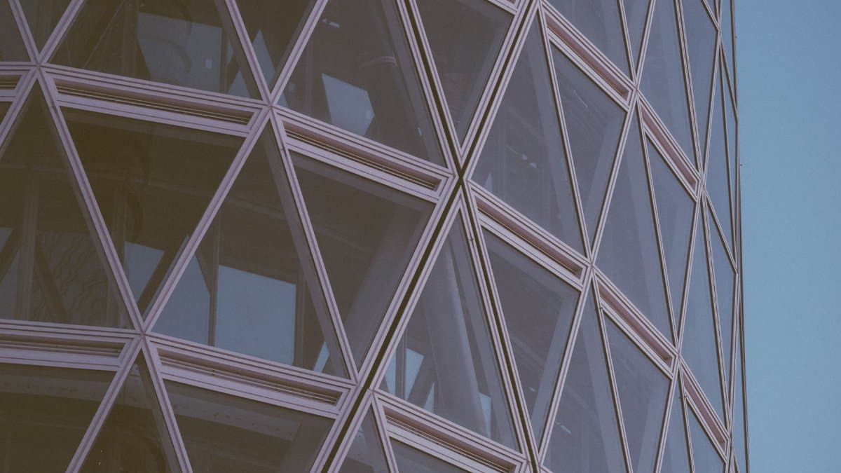 Close-up of a modern building's geometric facade with crisscross pattern and glass windows.