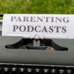 Close-up of an antique typewriter outdoors with focus on sheet labeled 'Parenting Podcasts'.