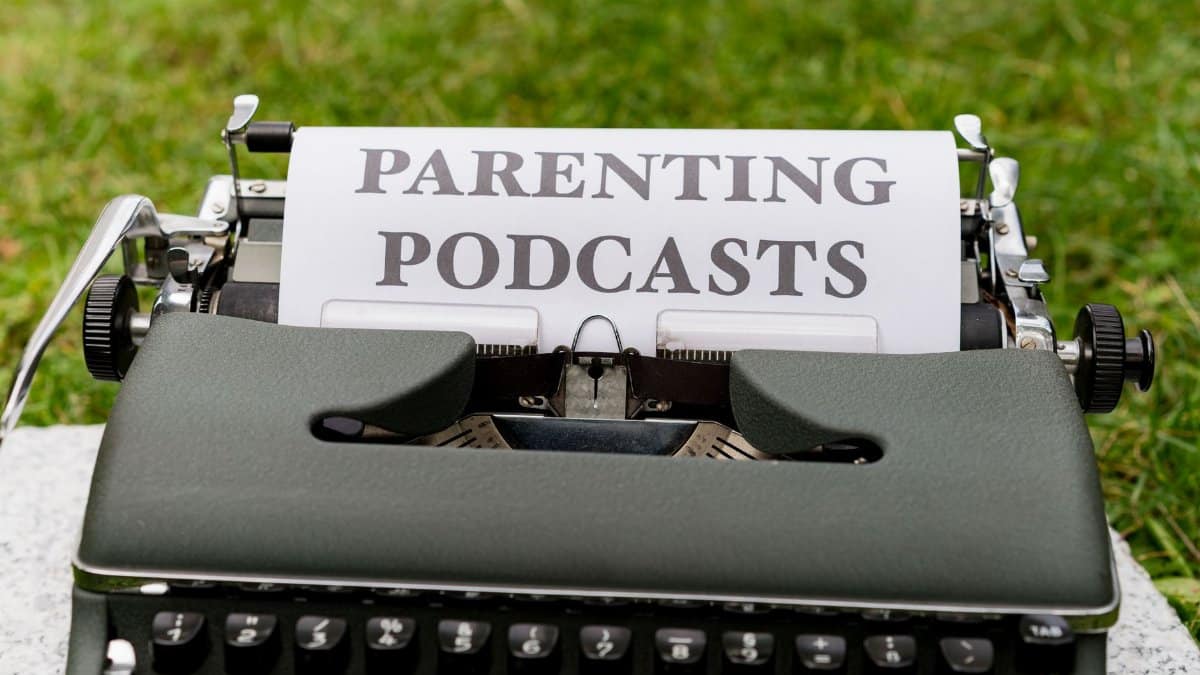 Close-up of an antique typewriter outdoors with focus on sheet labeled 'Parenting Podcasts'.