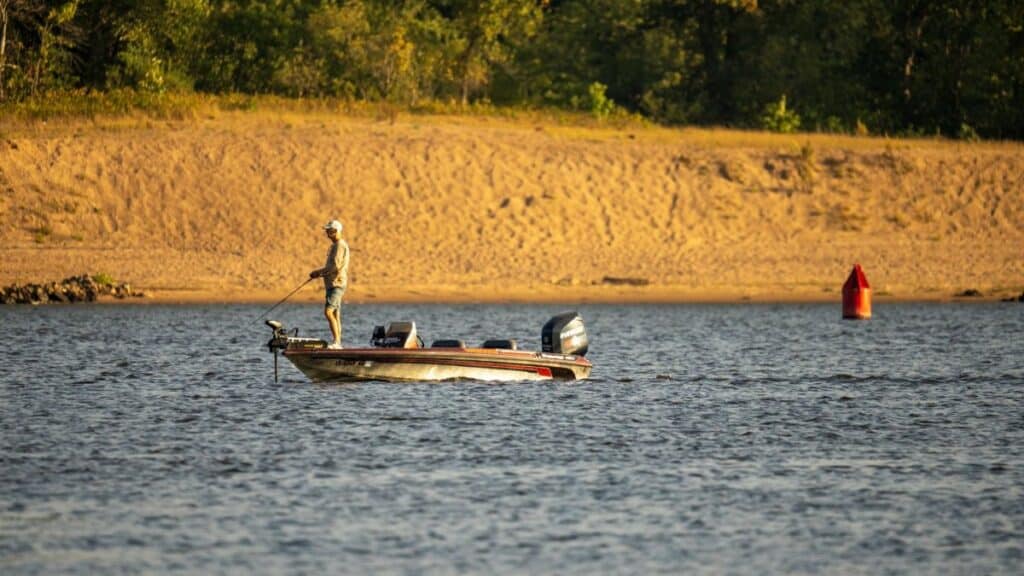 A lone fisherman in a boat casting a line on a tranquil river in Reads Landing, Minnesota.