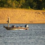 A lone fisherman in a boat casting a line on a tranquil river in Reads Landing, Minnesota.
