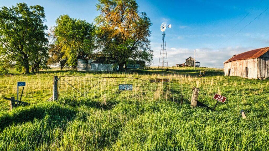 Charming rural farm scene in Minnesota with a windmill and wooden barns under a clear blue sky.