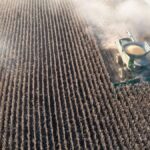 Aerial shot capturing a combine harvester working through a cornfield in rural Minnesota.