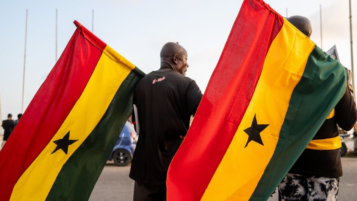 Two men holding Ghanaian flags during a public event in Ghana, capturing national pride.