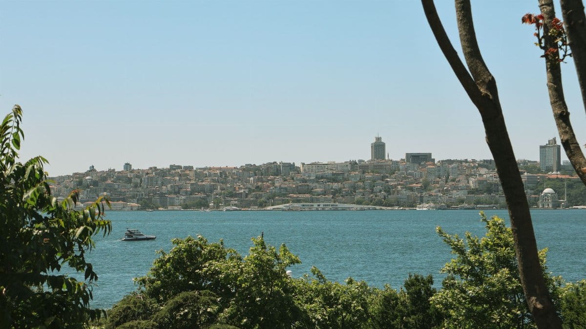 Beautiful view of Istanbul cityscape across the Bosphorus Strait with lush greenery and a passing boat.
