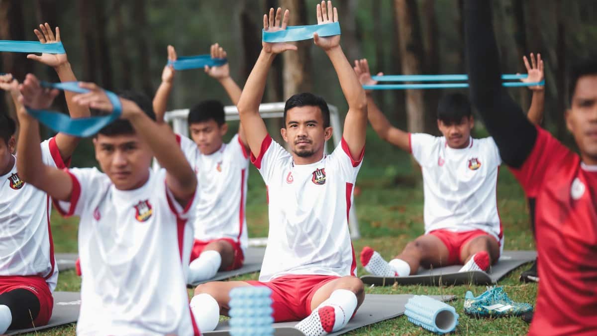 A group of young soccer players exercises with resistance bands during outdoor training.