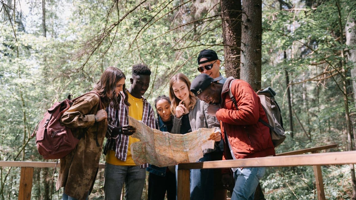 Group of diverse friends navigating a forest trail using a map. Perfect for adventure and travel themes.
