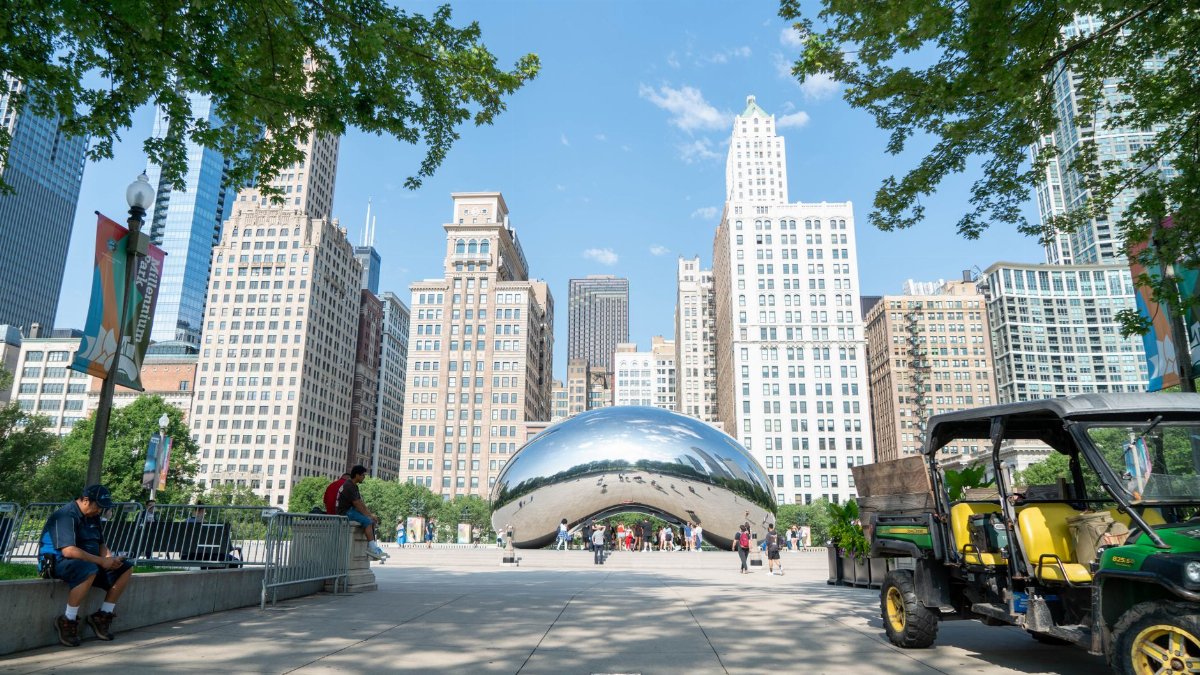 Cloud Gate sculpture in Chicago's Millennium Park with city skyline on a sunny day.