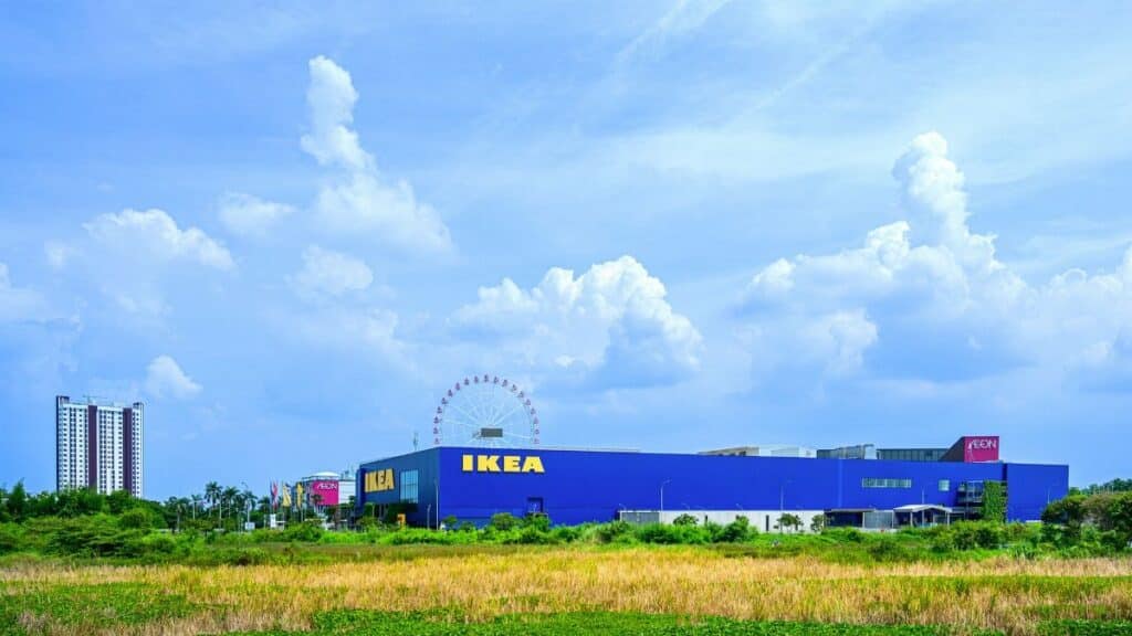 Vibrant IKEA store with a Ferris wheel against a blue sky backdrop, showcasing modern retail architecture.
