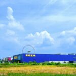 Vibrant IKEA store with a Ferris wheel against a blue sky backdrop, showcasing modern retail architecture.
