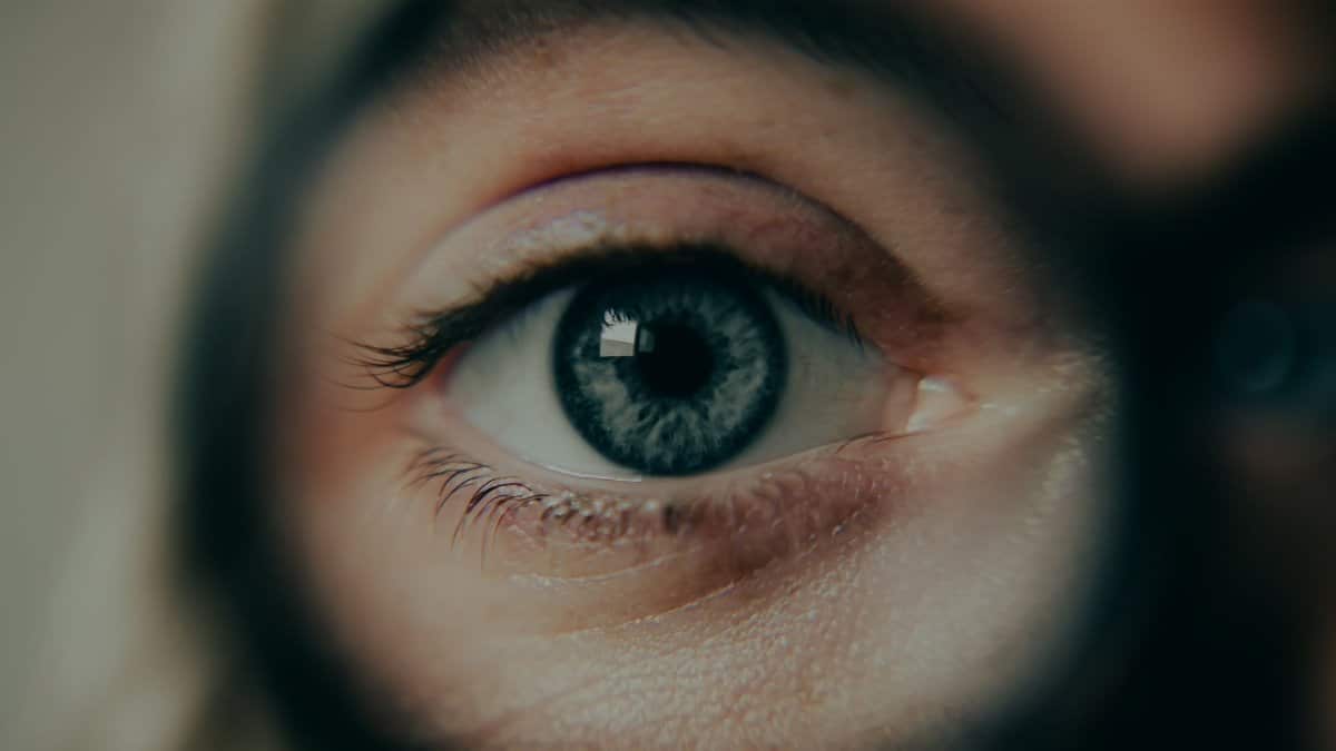 A detailed close-up of a blue eye magnified by a lens, showcasing intricate details.