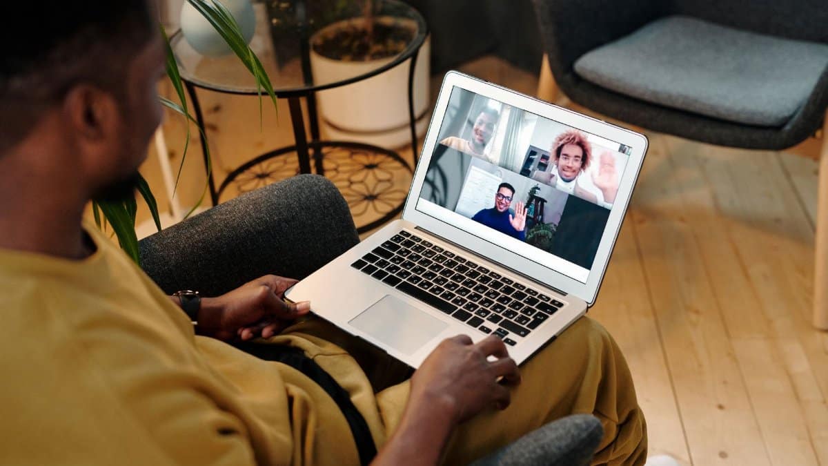 Person sitting in a chair using laptop for a virtual meeting in a cozy home office setting.
