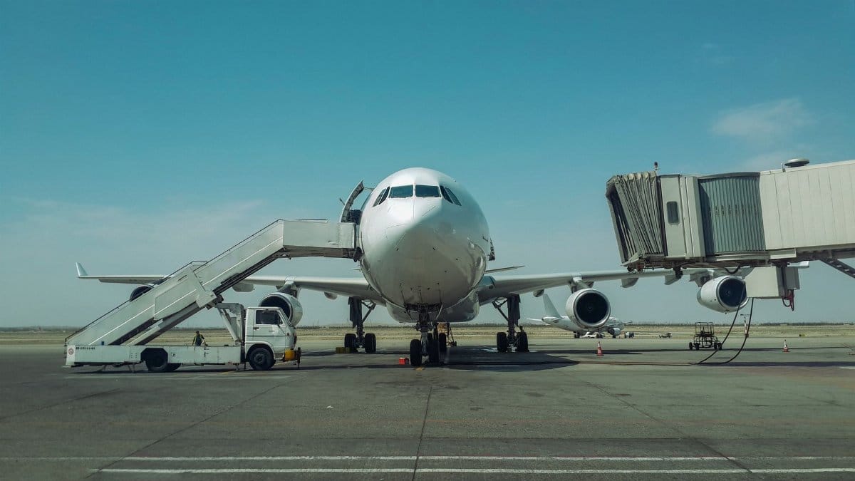 Large passenger plane stationed at Tehran airport with boarding stairs and bridge.