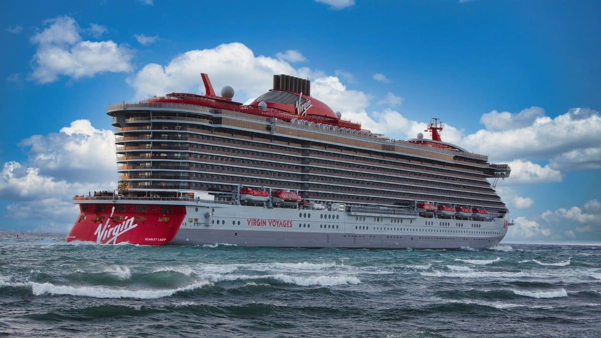 Experience the luxury of Virgin Voyages' Scarlet Lady cruise ship sailing through vibrant ocean waters.