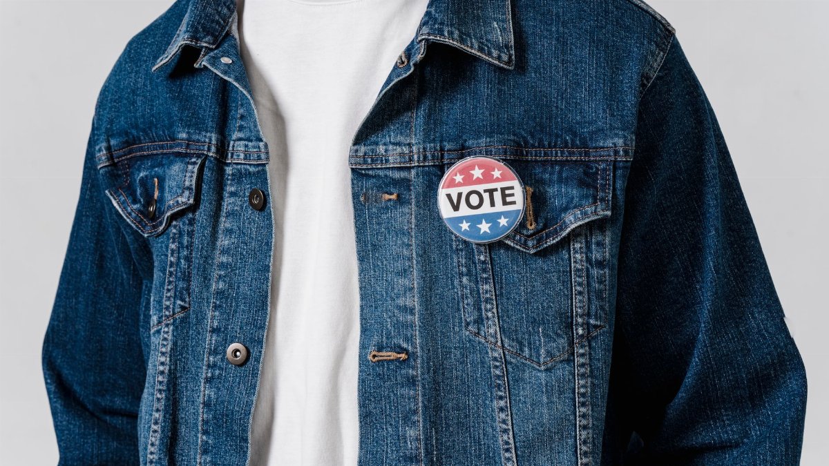 Close-up of a denim jacket with a patriotic vote badge promoting political engagement.