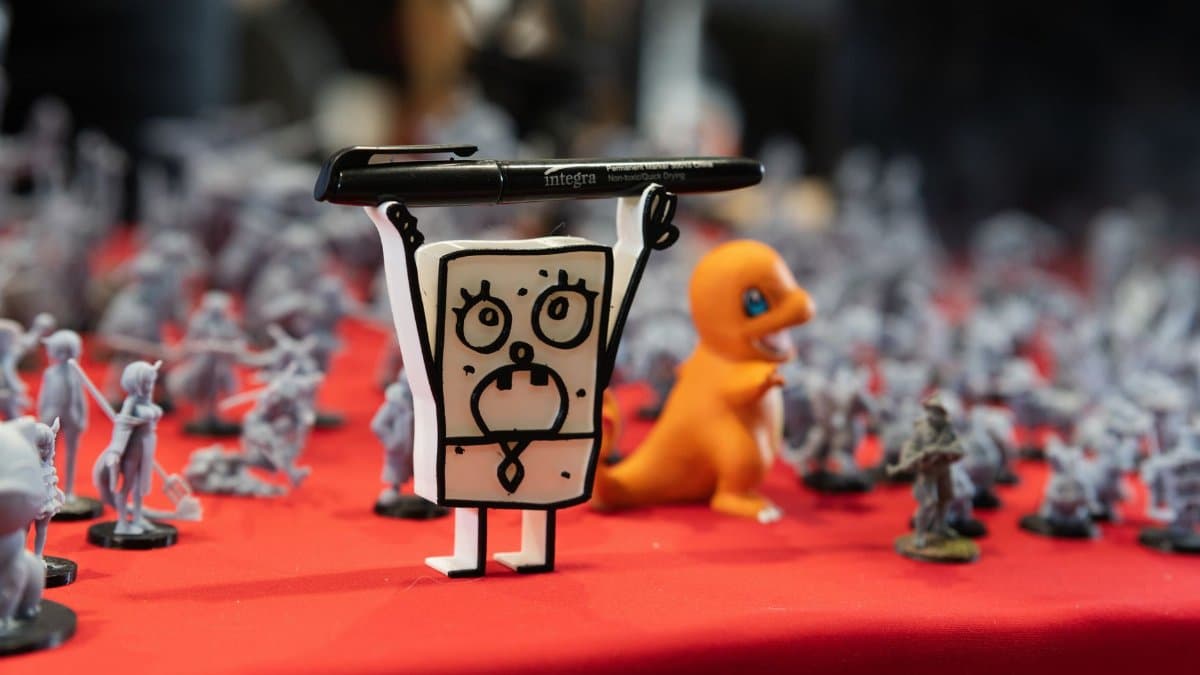Close-up of assorted figurines and toys displayed on a red table at a convention.
