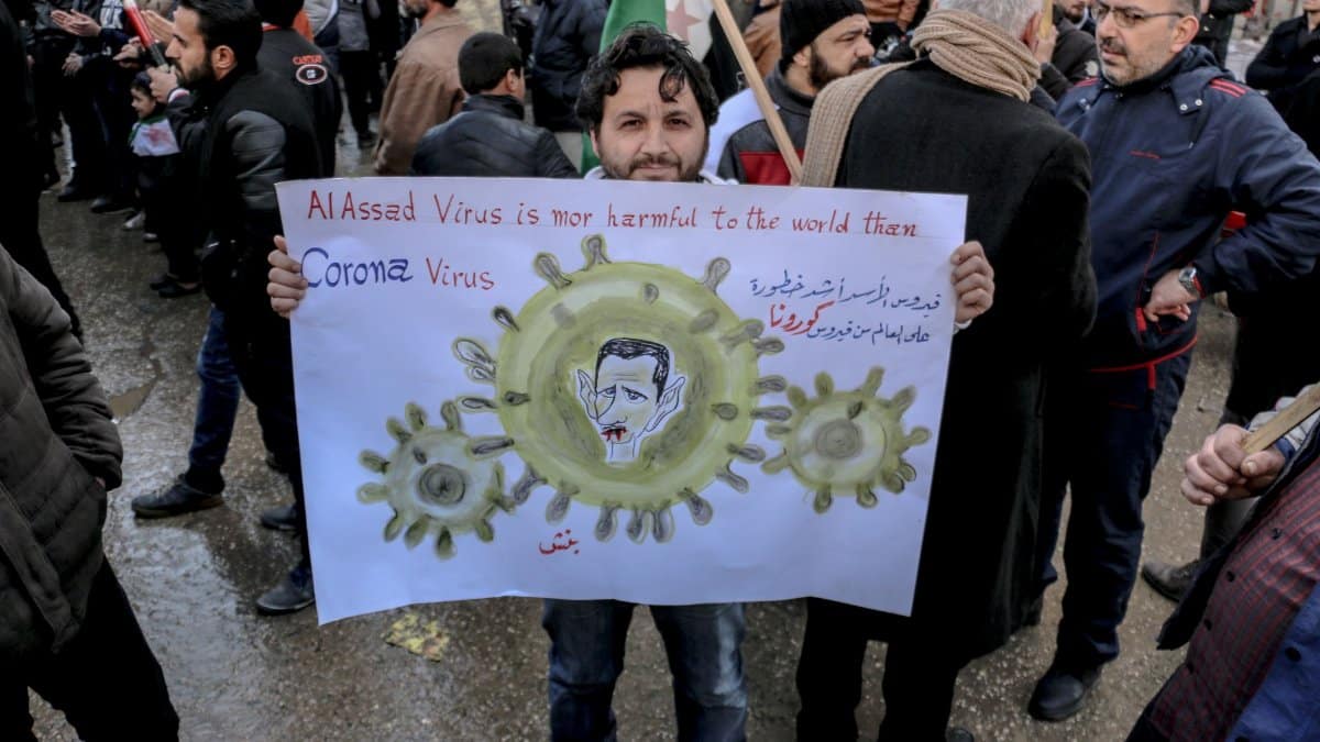 High angle of ethnic male activist with poster standing on crowded street at demonstration against policy