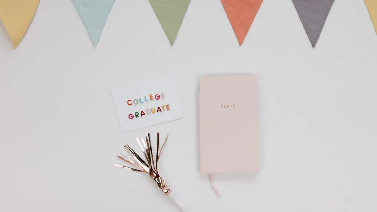 Flat lay of a graduation card, planner, and decorations for a college celebration.