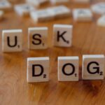 Scrabble tiles spelling 'DOGE' and 'MUSK' on a wooden table, highlighting internet culture and cryptocurrency.