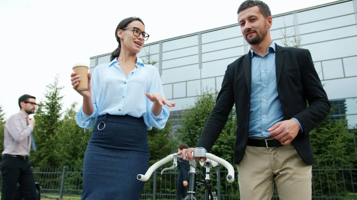 Business professionals walking and talking outside an office building, emphasizing collaboration.