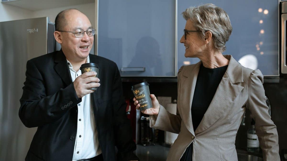 Two business professionals sharing a coffee break in a modern office kitchen.