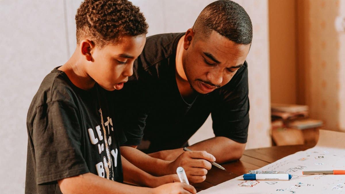 Father and son bonding over drawing indoors, fostering creativity and learning.