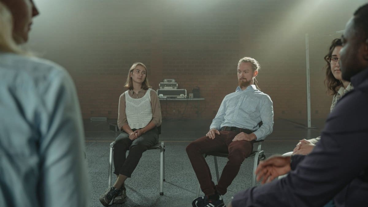 A diverse group of adults engaged in a thoughtful conversation indoors.