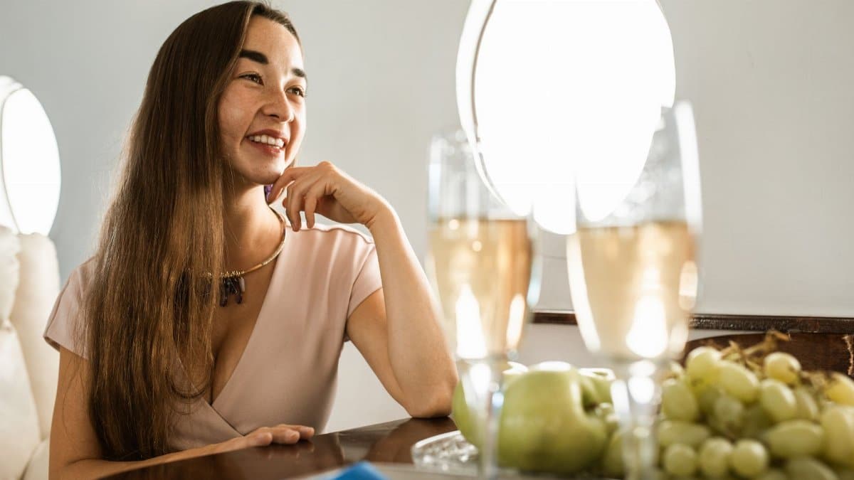 Woman relaxing in a private jet with champagne and fresh fruit, epitomizing luxury travel.