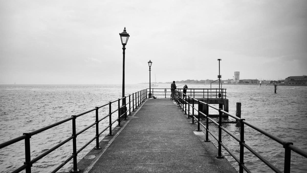Scenic view of a pier with railings and street lights leading into the river in Greater London.