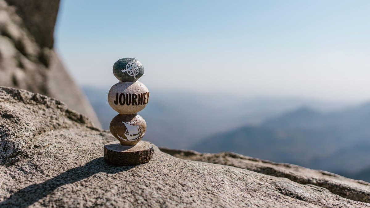 A serene image of stacked stones with 'Journey' text on a mountain peak.