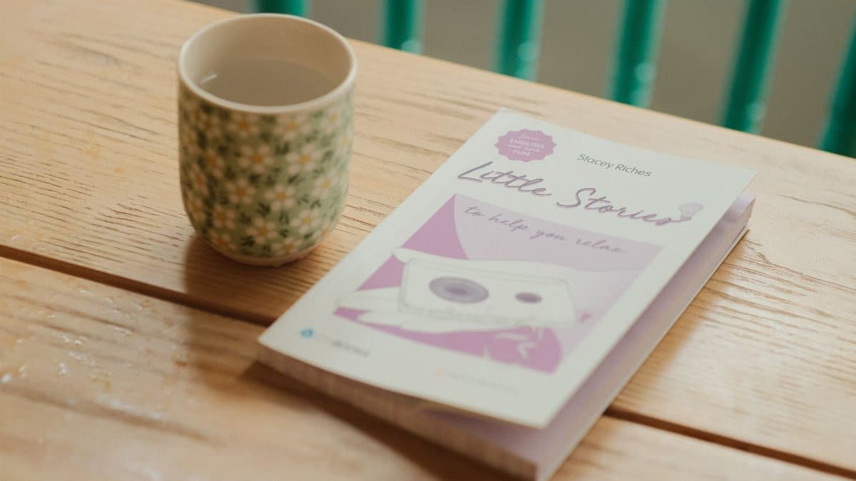 Cup of tea and book titled 'Little Stories' on wooden table, perfect for relaxing.