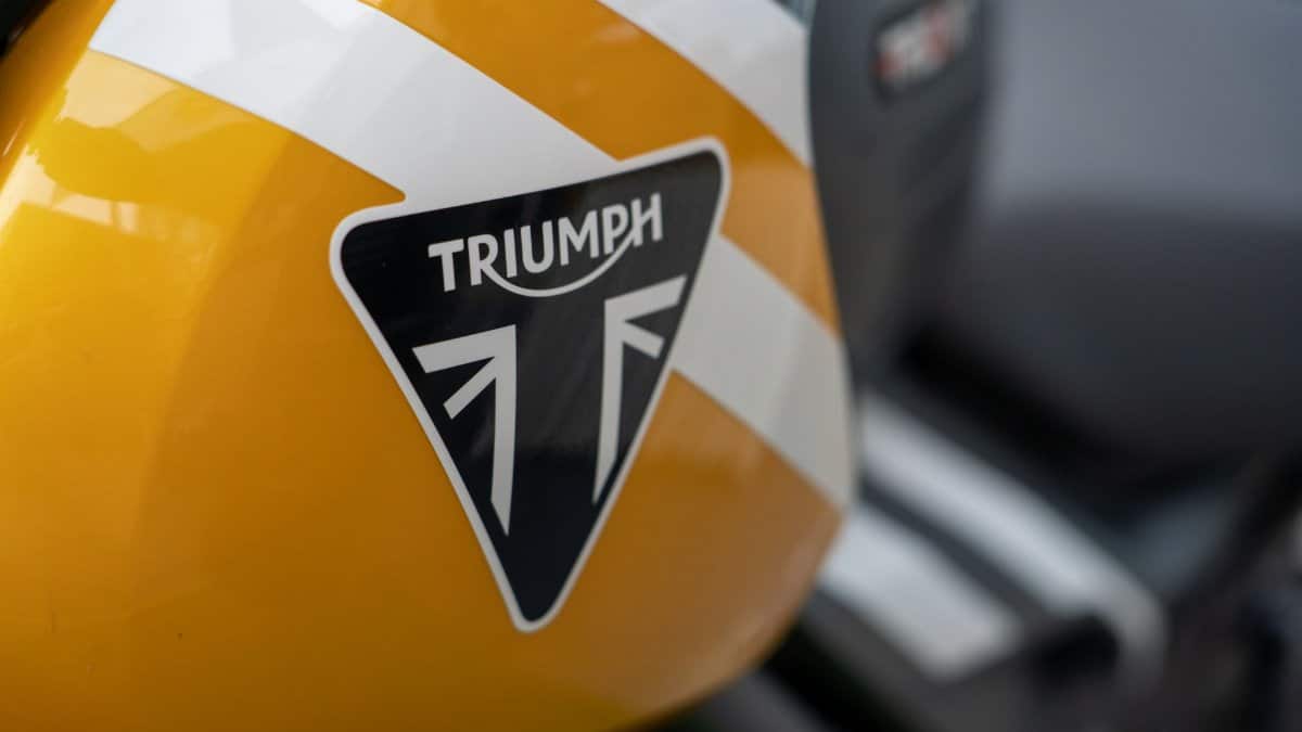 Detailed view of a yellow Triumph motorcycle fuel tank showcasing its logo.