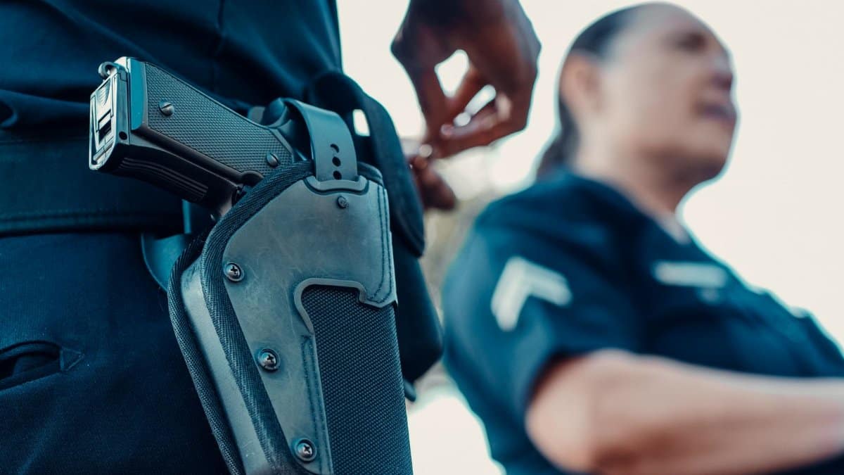 Police officers with a focus on a holstered handgun, demonstrating law enforcement readiness.