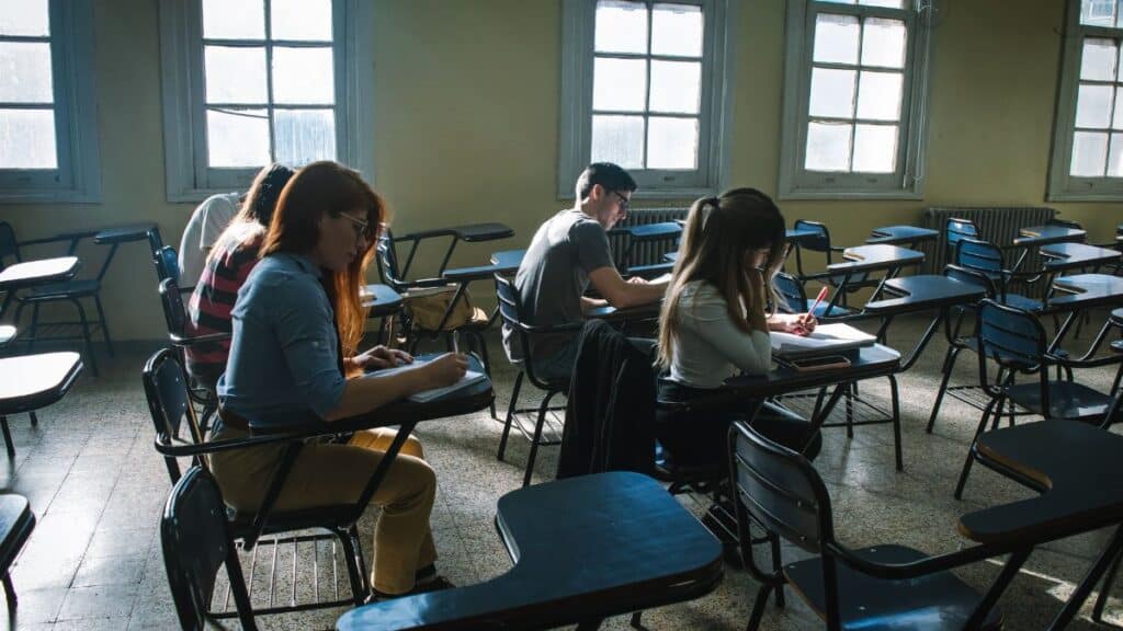A group of students focused on taking a test in a sunlit classroom setting.