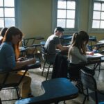 A group of students focused on taking a test in a sunlit classroom setting.