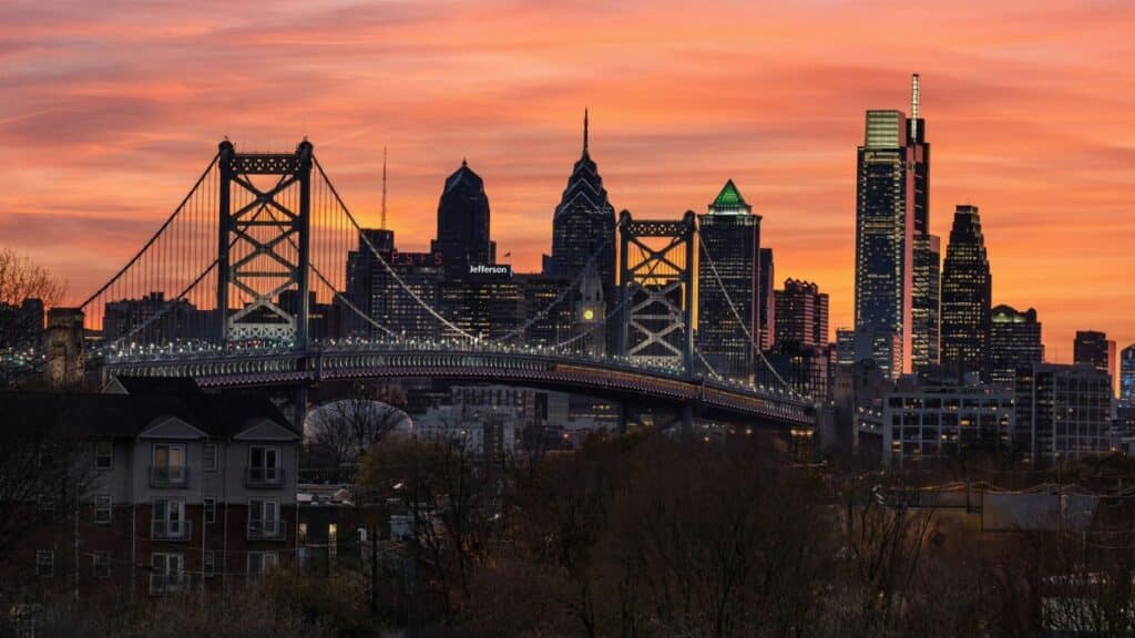 Stunning view of Philadelphia skyline and Ben Franklin Bridge at sunset, showcasing city architecture.